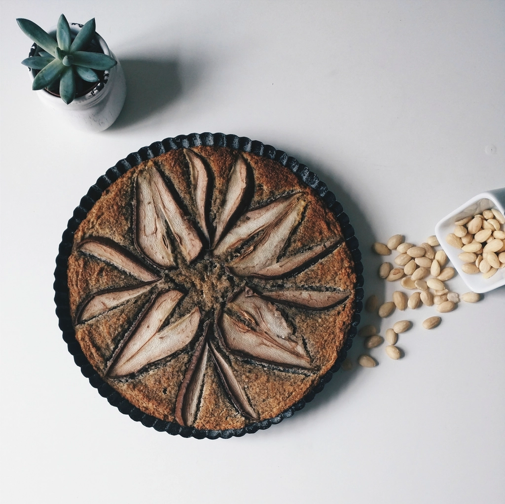 Almond tart beside a bowl of blanched almond kernels